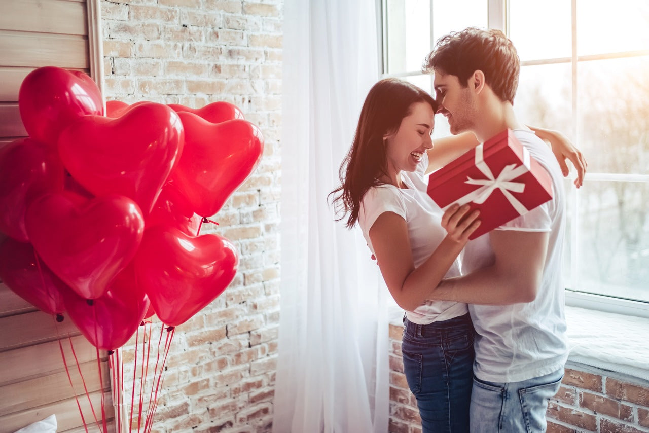 young couple who hug each other a heart shaped balloons